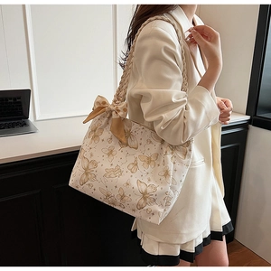 Detail view of butterfly print tote bag with woven straps and decorative silk scarf bow
