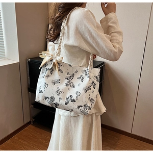 Close-up of white butterfly print tote bag with decorative yellow silk scarf details