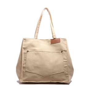 Minimalist beige canvas tote bag with V-shaped pocket and rivet details for women