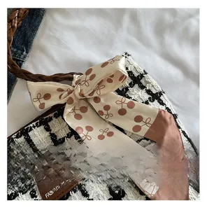 Detail of plaid wool tote bag with woven leather handle and cherry pattern silk ribbon