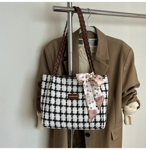 Detail of tweed checkered tote bag featuring leather handles and decorative silk scarf