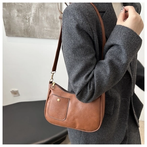 Detail of caramel brown faux leather underarm bag featuring gold studs and front pocket