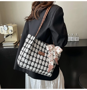 Detail of checkered wool tote bag featuring woven leather strap and decorative silk scarf
