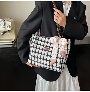 Close-up of houndstooth tote bag with pink cherry bow scarf and woven straps on model