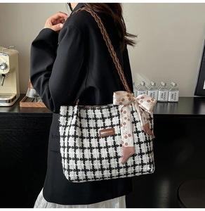 Detail of tweed tote bag with classic plaid pattern and decorative silk scarf on the strap
