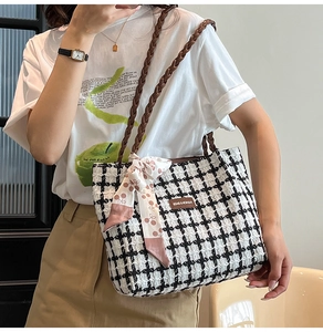 Detail of plaid wool tote bag featuring brown woven handles and pink decorative silk scarf