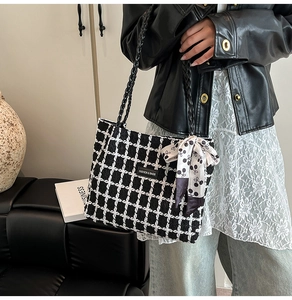 Detail of checkered tweed tote bag with woven handles and decorative scarf accessory