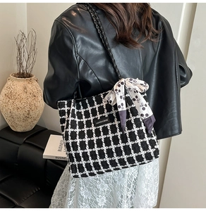 Detail of black and white plaid tweed tote bag with woven strap and silk scarf