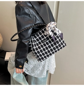 Detail of tweed checkered tote with black leather strap and decorative bow scarf