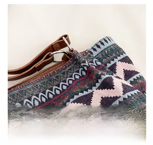 Detail view of woven bohemian bag featuring silver metallic thread and brown leather strap