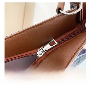 Macro shot of silver brushed metal zipper and stitching on brown leather tote bag