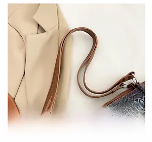 Close-up of brown leather shoulder strap and metallic ring on ethnic woven bag