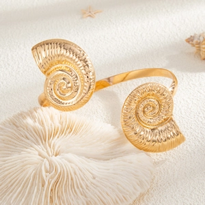 Macro-opname van gouden zeeslak-armband op wit zand met koraal en een zeester decoratie