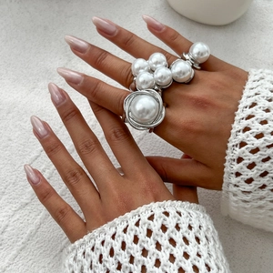 Elegant silver geometric ring set with white pearls on a soft white knit background