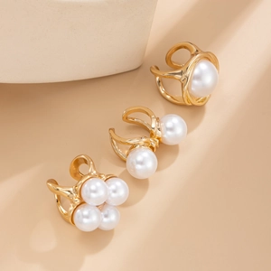 Detailed view of three gold pearl ear cuffs with single and clustered faux pearl designs