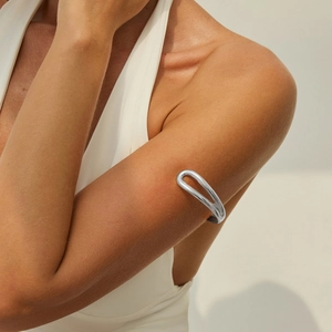 Detail van de gepolijste zilveren bovenarmband met een minimalistisch opengewerkt design