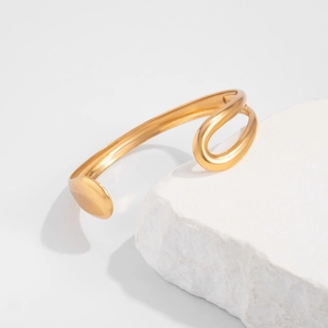 Detailopname van een gouden zeester- en schelp-armring op een gestructureerde steen