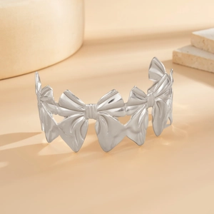 Zilveren open armband met uitgesneden strikpatroon op een minimalistische stenen voet