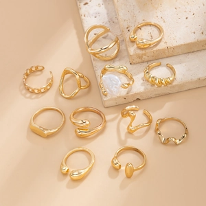Detail of 11-piece gold ring set with baroque pearls on a travertine stone background