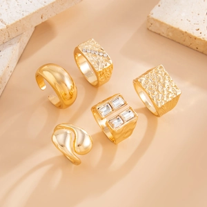 Close-up of a 5-piece gold ring set featuring hammered textures and crystal accents