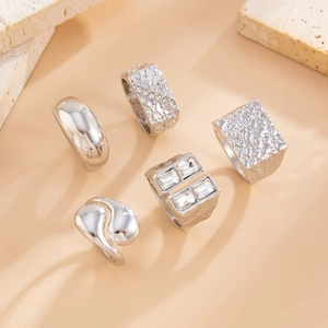 Detailed view of five silver rings featuring minimalist, textured and crystal accents