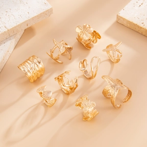 Detail of 9-piece gold starfish and seashell ring set on stone aesthetic background