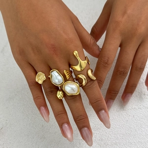Gros plan d'un ensemble de bagues dorées style lave et perles portées par un mannequin