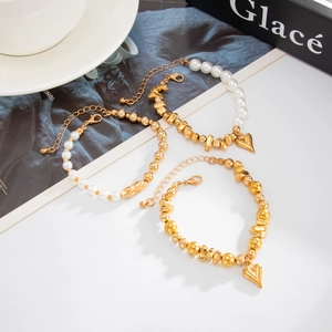 Detailansicht goldener Perlenarmbänder mit Herzanhängern und Karabinerverschlüssen für Damen