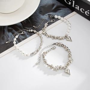 Detailansicht von silbernen Herzanhängern und Kunstperlen an einem Armband-Set