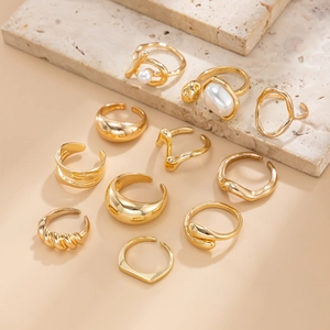 Detailed set of 11 golden rings with imitation pearls on a natural stone display