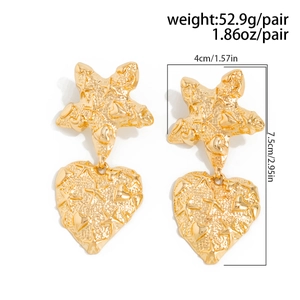 Detail showing oversized gold heart and starfish earrings with hammered texture and dimensions