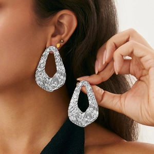 Close-up of oversized silver irregular droplet earrings with liquid metal ripple texture
