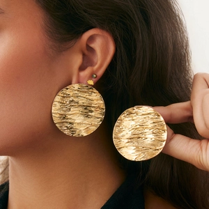 Macro view of gold irregular wavy earrings showing textured surface on model