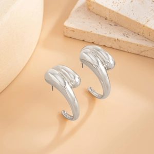 Close-up of chunky C-shape molten silver metal earrings with wavy liquid texture finish