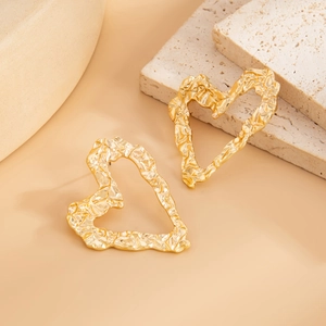 Detailed view of large golden hollow heart earrings with unique crumpled metal texture