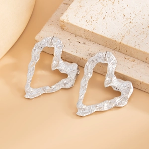 Macro shot of silver oversized heart earrings with hammered metal texture on stone