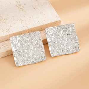 Macro shot of silver square earrings with unique pleated metal texture on stone