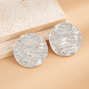 Macro detail of silver U-shaped earrings with hammered irregular water ripple texture