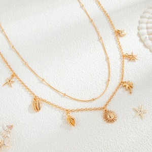 Close-up of gold double-layer chain with starfish, shell and coconut tree charms