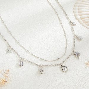 Macro detail of silver layered ocean chain with starfish, shell, and palm tree charms