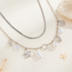 Detail of silver beach style waist chain with starfish, shells and baroque pearls on sand