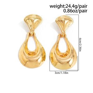 Macro detail of large gold lava-style earrings showing dimensions and heavy metal texture