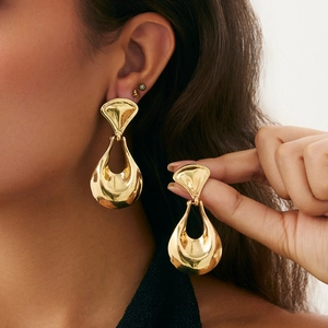 Detail view of large irregular geometric gold earrings with polished hollow drop design