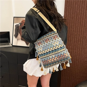 Détail d'un sac bohème tissé avec des motifs géométriques et des pompons multicolores