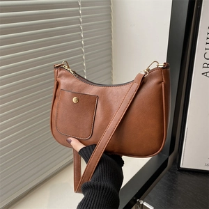 Close-up of vintage brown PU leather half-moon shoulder bag with golden button detail