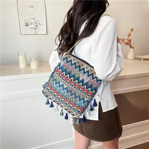 Détail d'un sac bohème tissé avec motifs géométriques et pampilles bleues et blanches