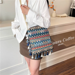Détail d'un sac bohème en tricot avec motifs zigzag colorés et longues franges de glands
