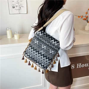 Détail d'un sac bohème avec motifs de vagues géométriques et pompons à franges marron