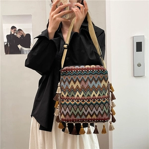 Détail d'un sac bohème tissé avec motifs géométriques colorés et franges à pompons denses