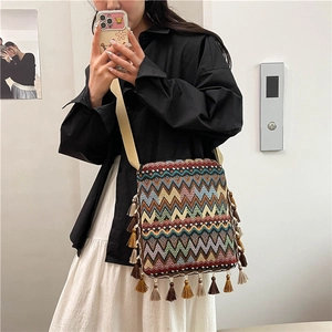 Détail d'un sac bohème tissé avec des motifs colorés et des pompons à franges
